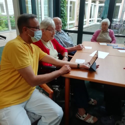 Senioren lassen sich den Umgang mit einem Tablet zeigen